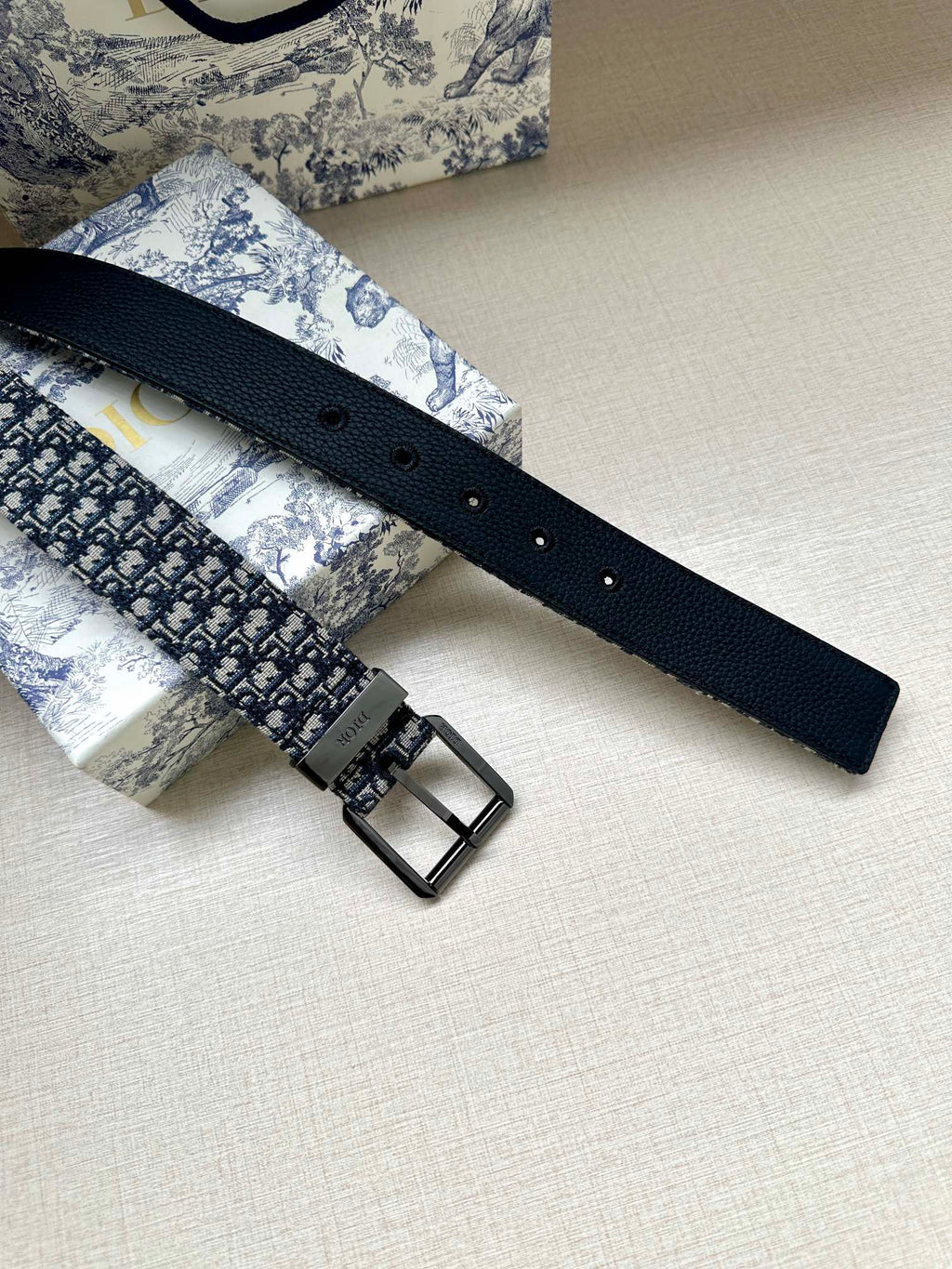 Dior belt with black leather tail and silver rectangular buckle over blue jacquard
