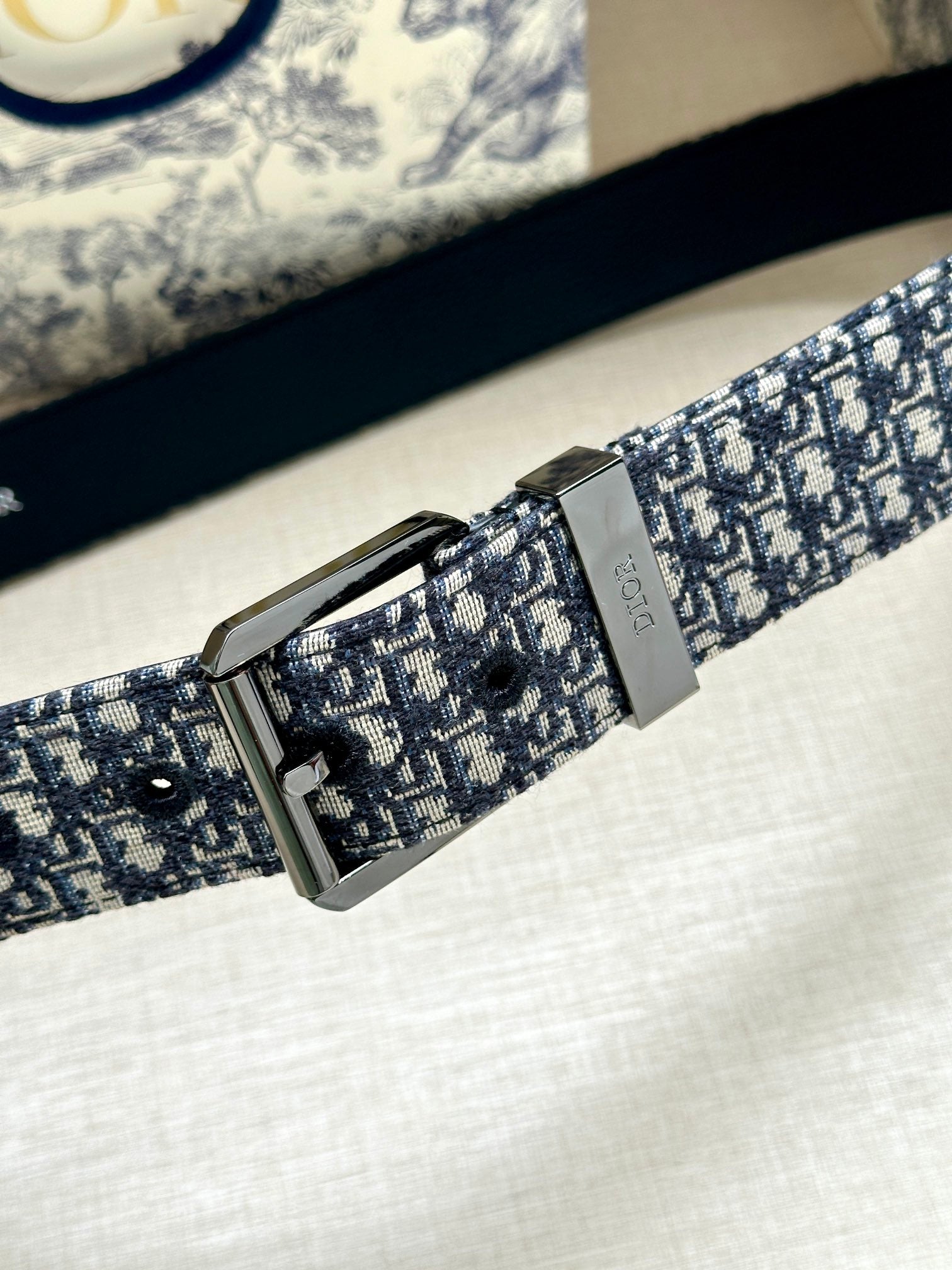Dior belt close-up: blue jacquard strap with silver buckle and engraved keeper