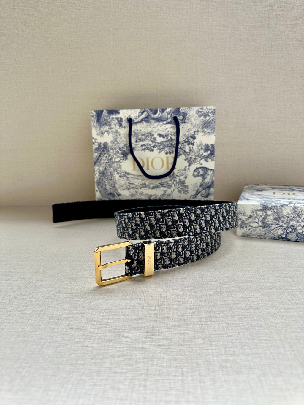 Navy Dior belt with Dior monogram pattern and gold buckle, laid flat