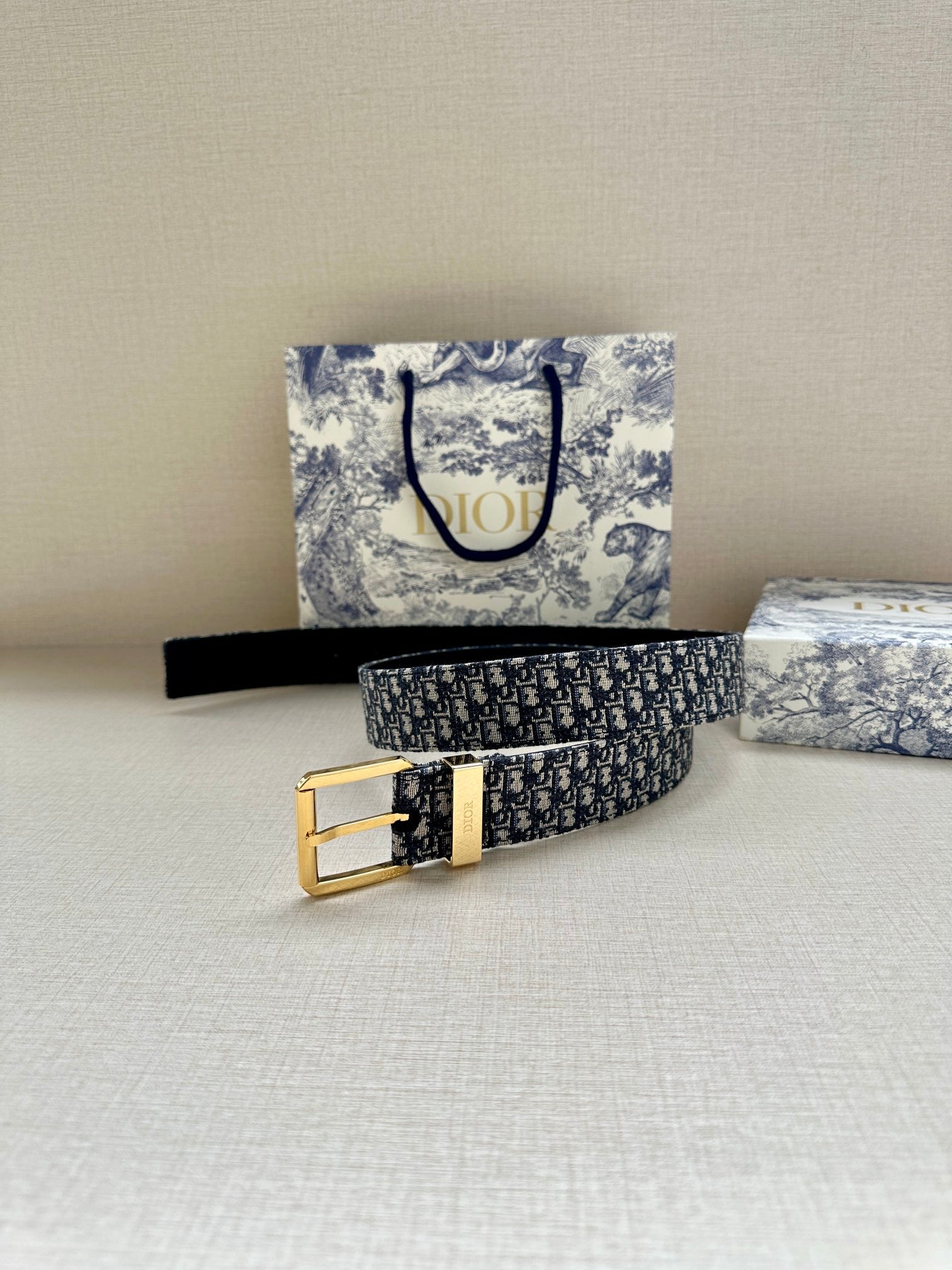 Navy Dior belt with Dior monogram pattern and gold buckle, laid flat
