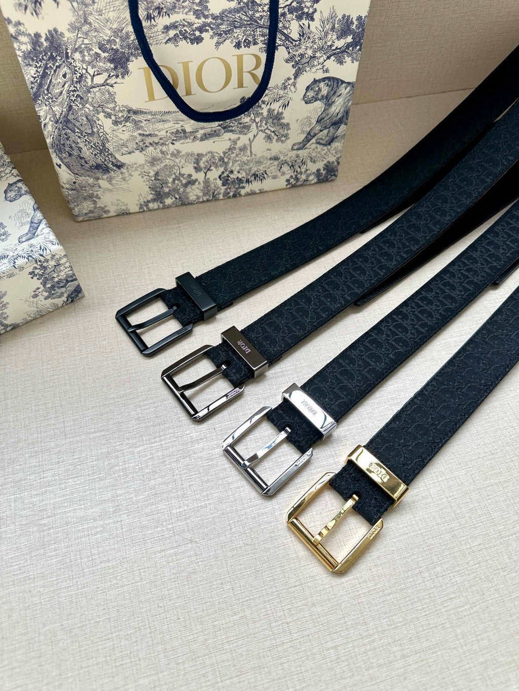 Multiple Dior belt straps with different buckle finishes: black, silver, and gold
