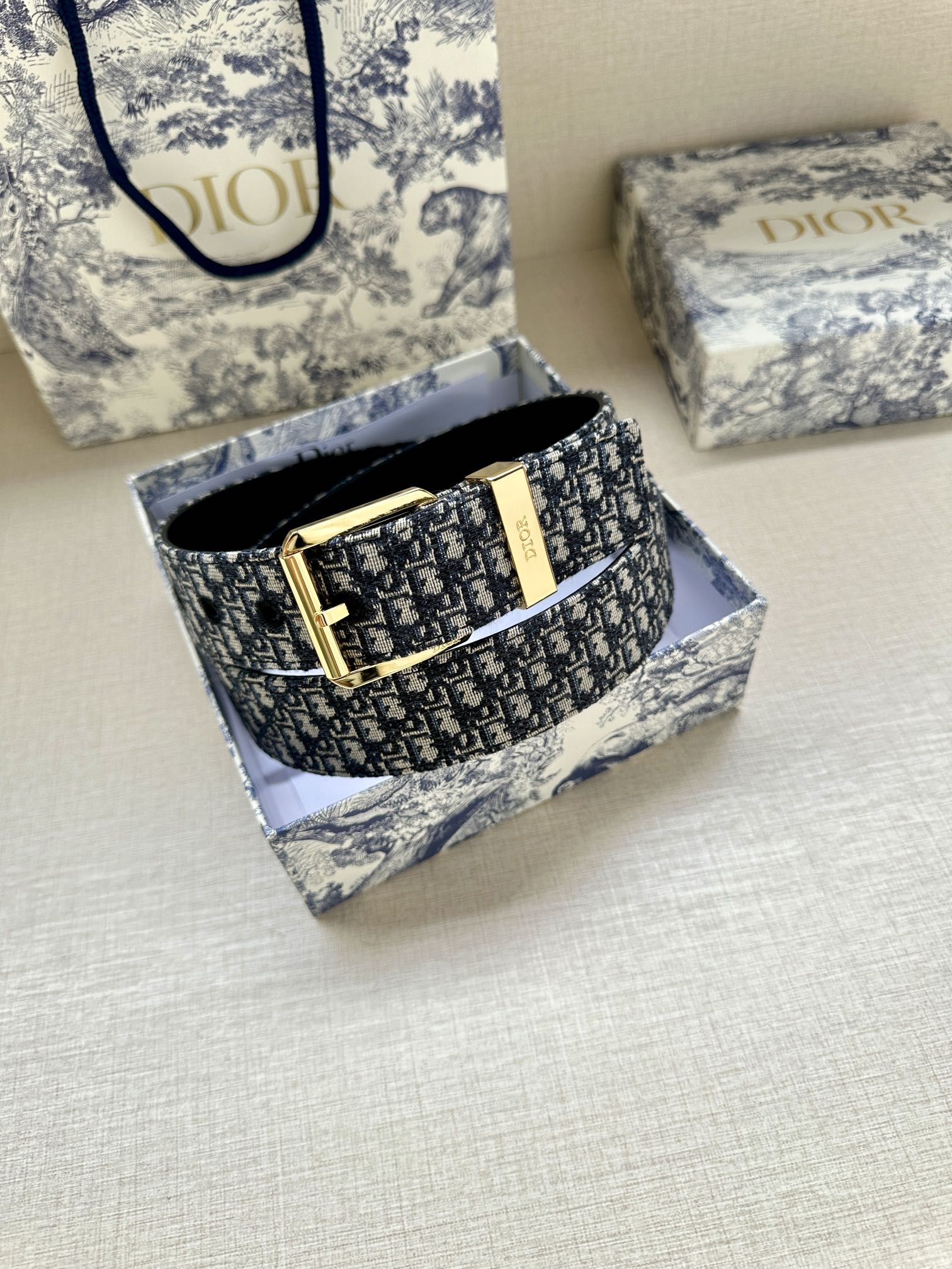 Dior monogram belt with gold buckle shown in box and black belt underside