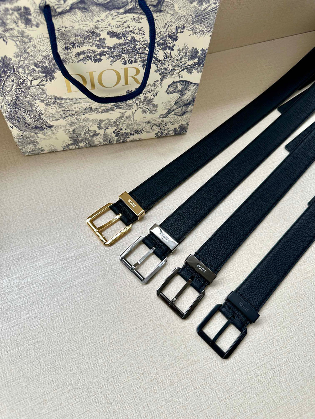 Assorted Dior belt straps with buckles in gold, silver, and black on navy webbing