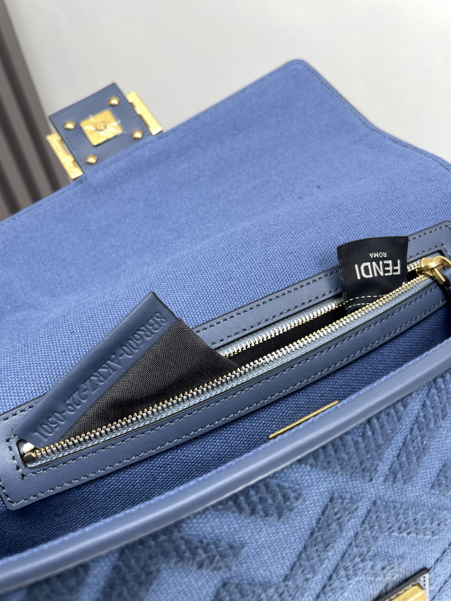 Blue Fendi bag close-up of zipper and metal pull with gold hardware