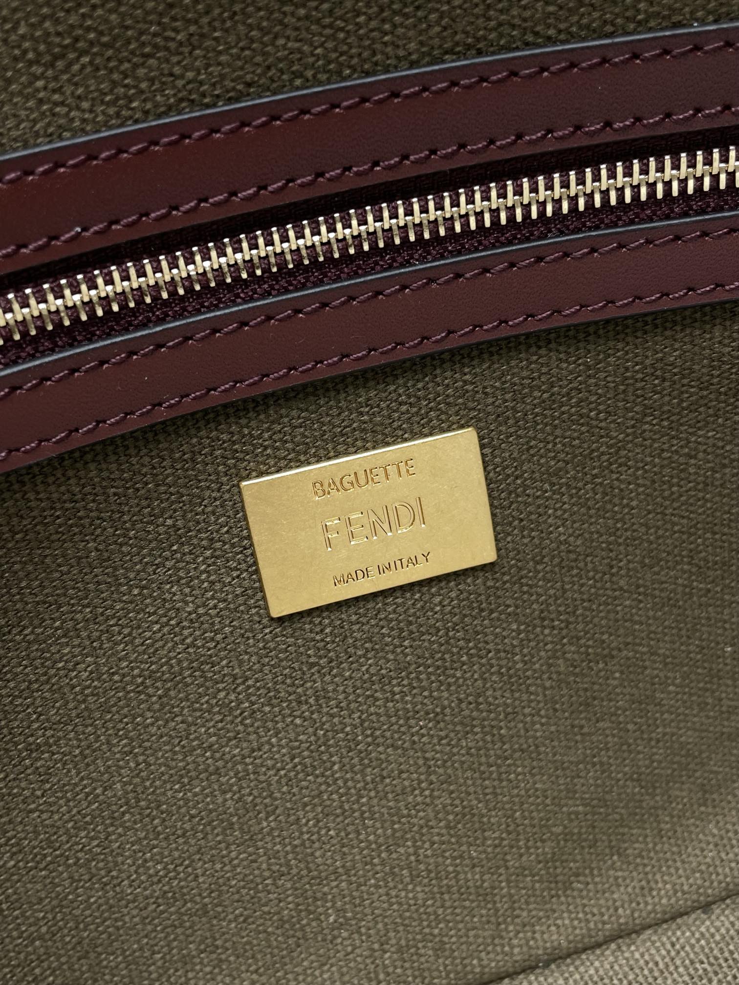 FENDI label on Fendi baguette bag interior, gold tag with olive canvas and burgundy trim