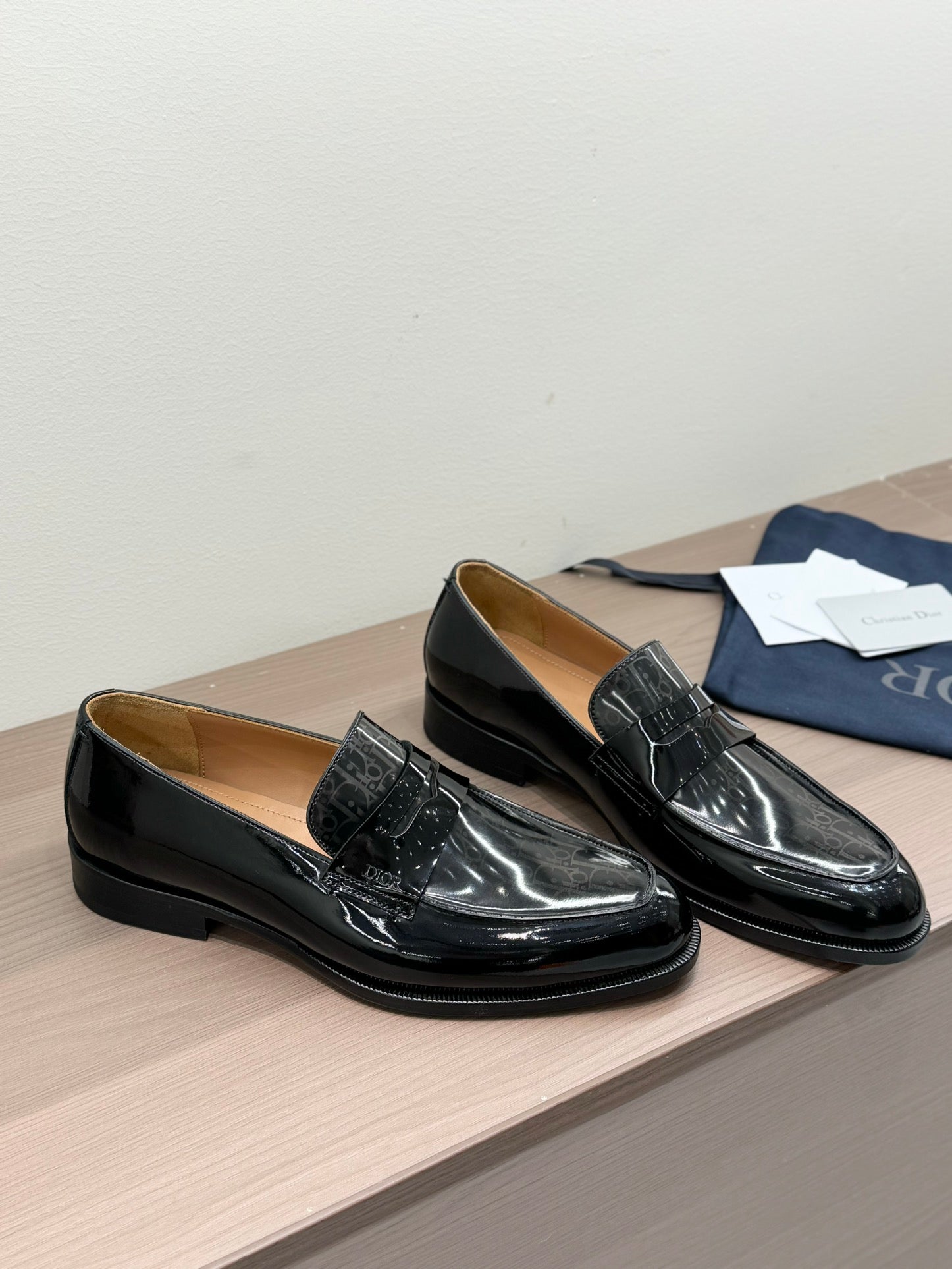 Unisex black patent loafers pair, low heel and buckle strap, angled front view
