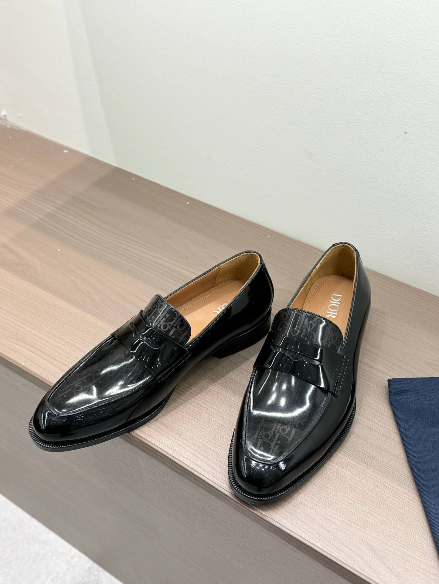 Unisex black patent loafers with front buckle detail, two shoes side by side