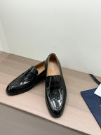 Unisex black patent loafers with front strap buckle, single shoe view