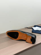 Unisex black patent loafers, outsole and tan interior visible, underside side view