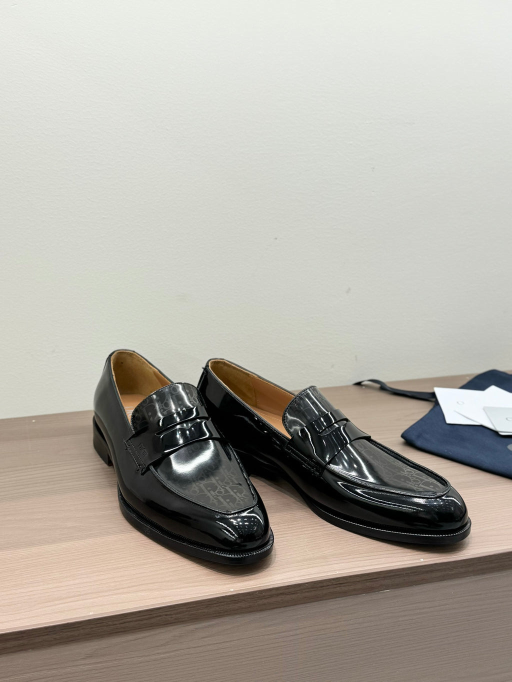 Unisex black patent loafers with front buckle, rounded heel, angled view