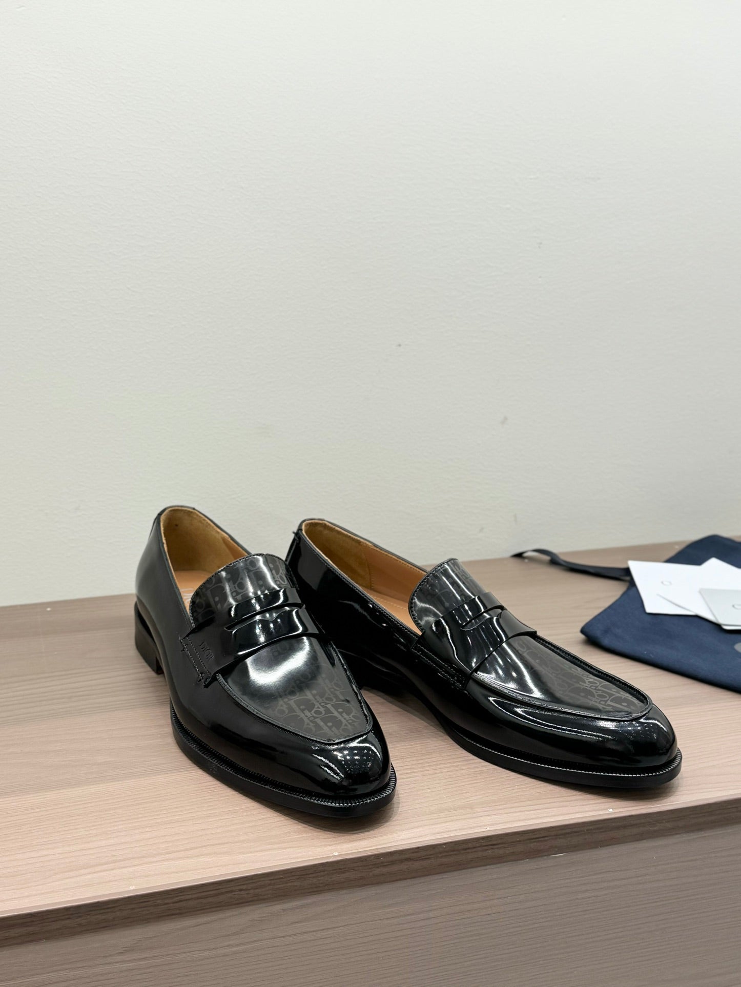 Unisex black patent loafers with front buckle, rounded heel, angled view