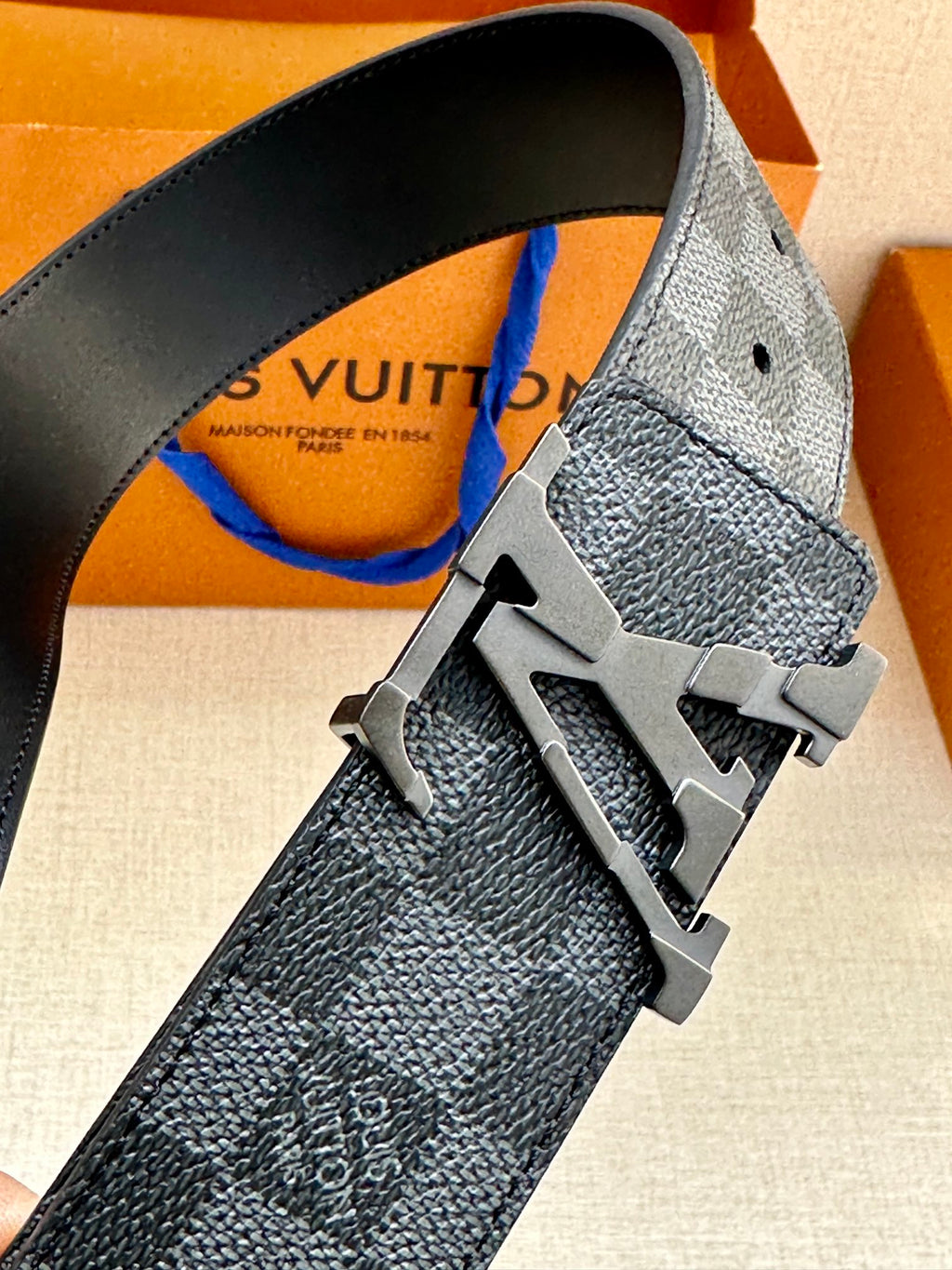 Louis Vuitton fabric belt close-up with metal buckle featuring LV logo