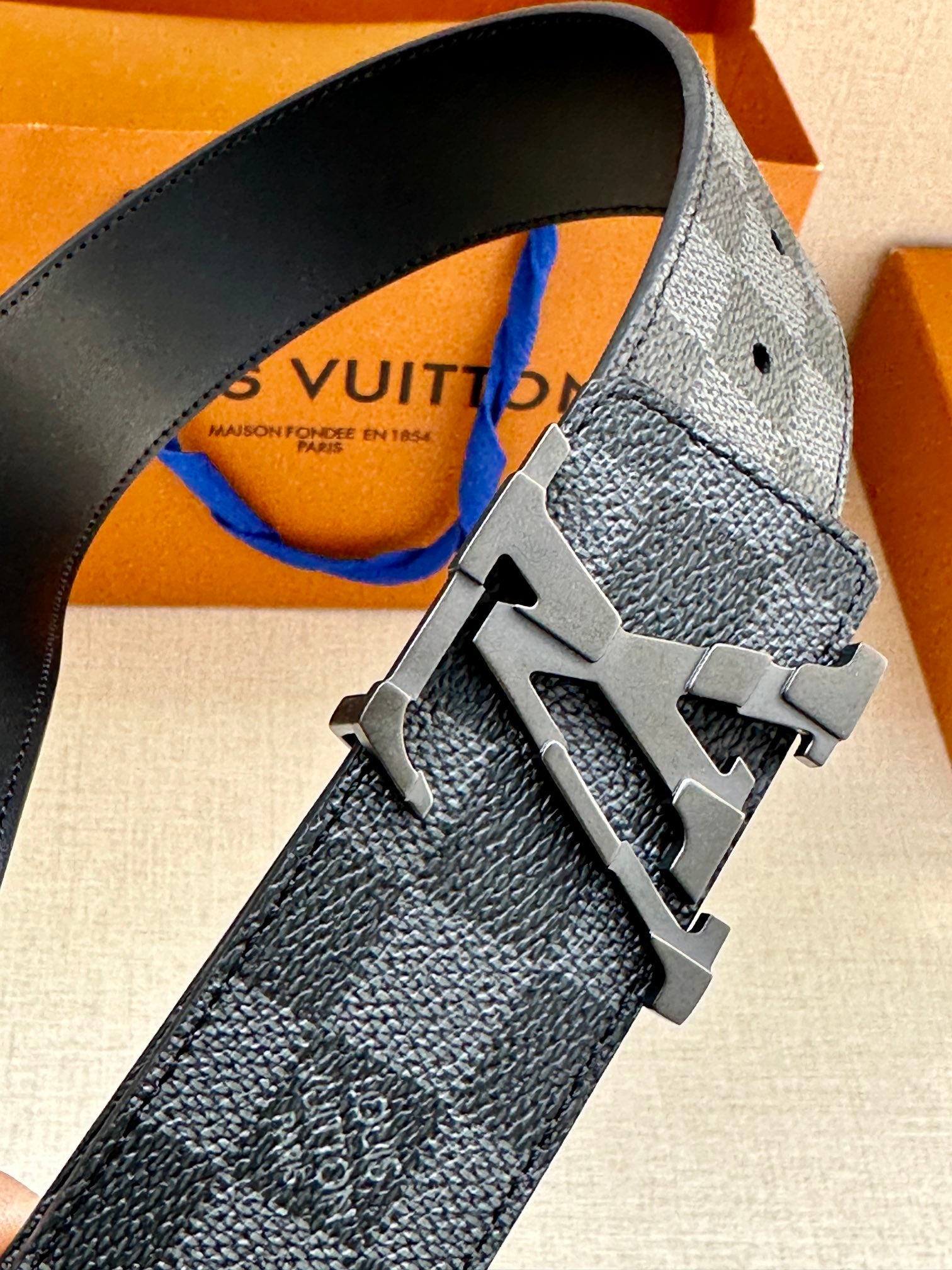 Louis Vuitton fabric belt close-up with metal buckle featuring LV logo