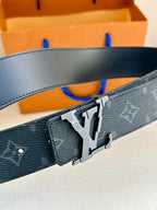 Close-up of dark monogram belt buckle with silver-tone metal clasp