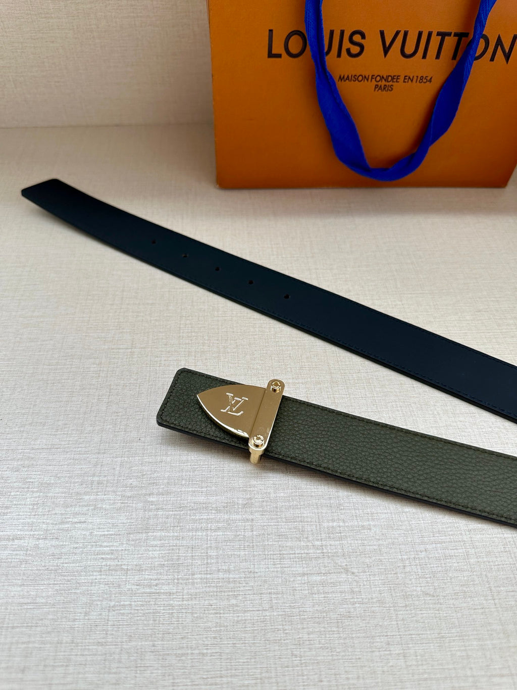 Louis Vuitton leather belt laid flat in dark green with silver-tone logo buckle