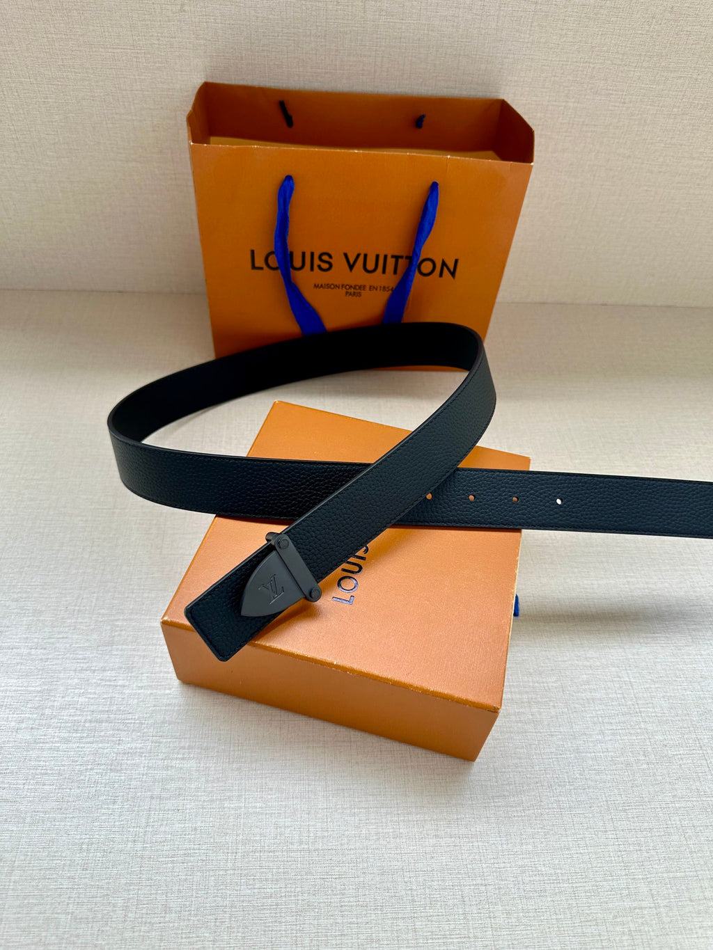 Louis Vuitton dark blue leather belt with silver buckle, shown laid across display