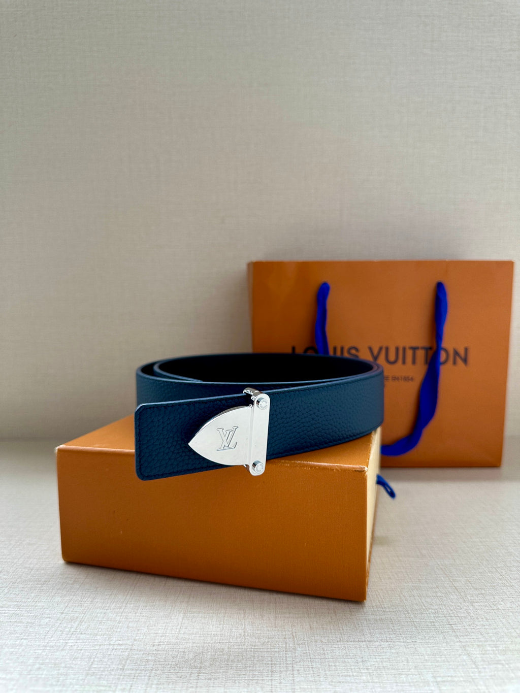 Blue leather belt with silver LV buckle, laid flat
