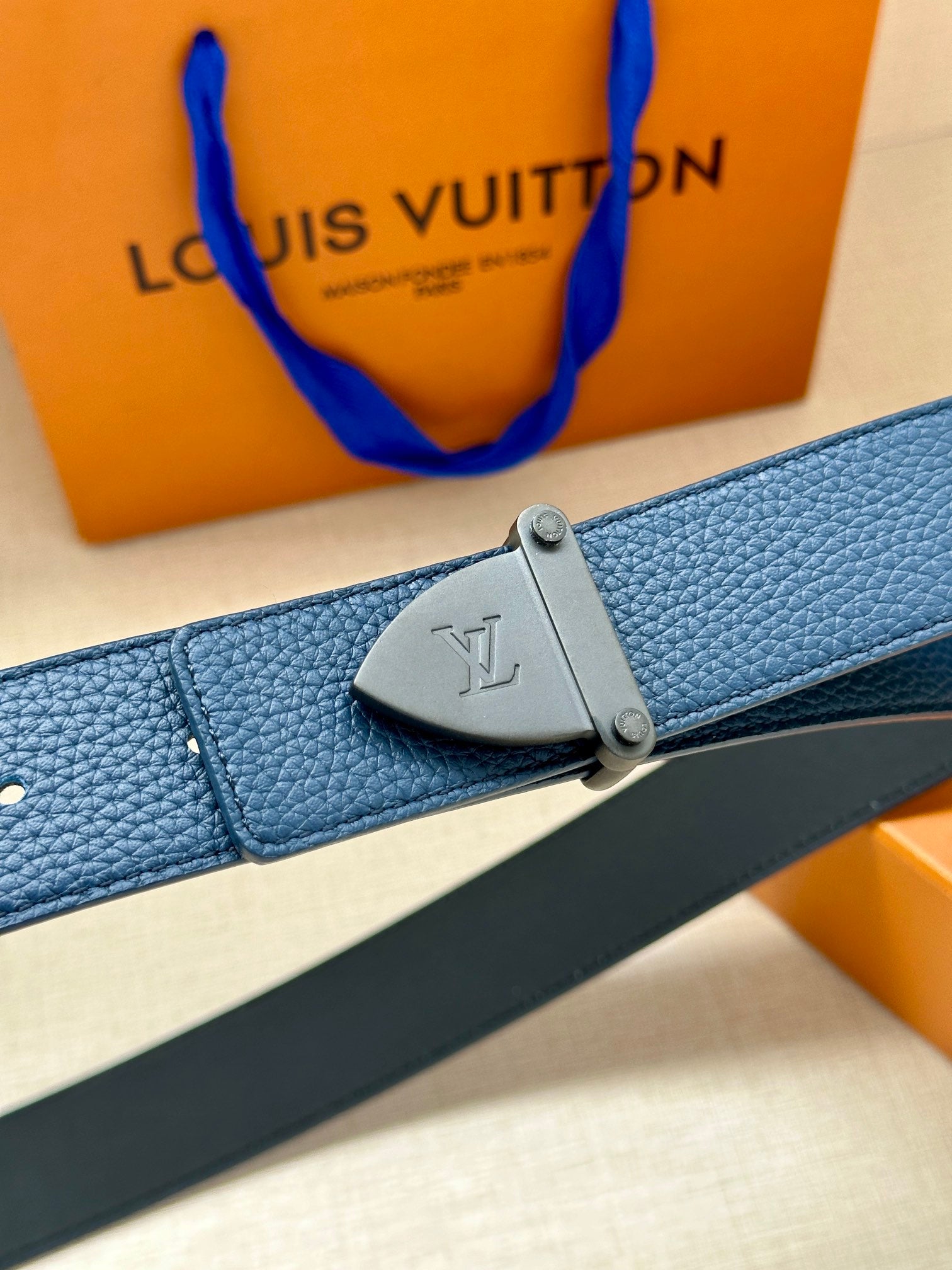 Louis Vuitton belt close-up: blue textured strap and silver-tone buckle