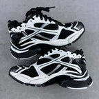 Balenciaga unisex sneaker pair, white and black, side-by-side on gray surface