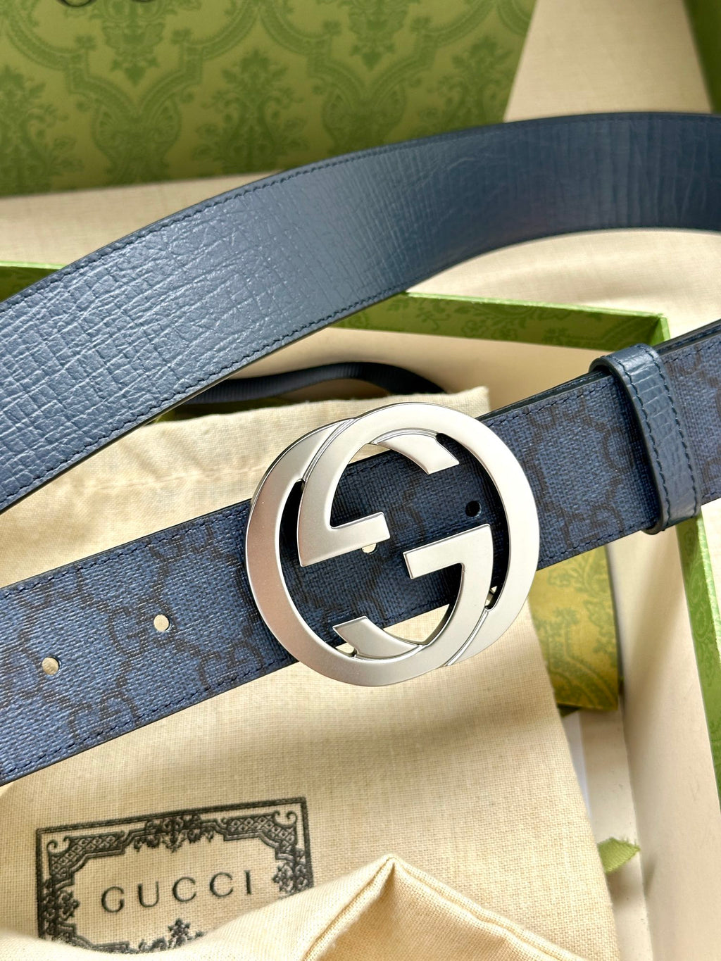 Gucci belt buckle close-up, navy blue leather strap with silver-tone GG