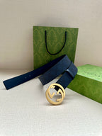 Gucci belt with navy strap and gold-tone GG buckle, resting on folded packaging