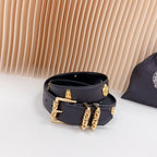 Navy leather belt with gold buckle hardware and charm details on the strap ends
