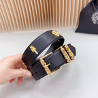 Navy leather belt with gold buckle and ornate charm plates, held in hand