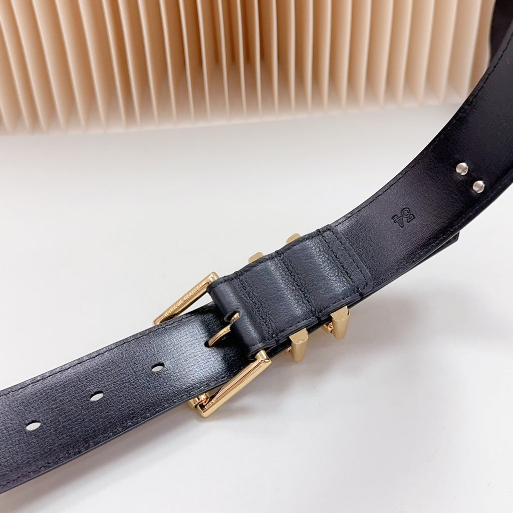 Navy leather belt with gold buckle and cross charm detail, angled close-up