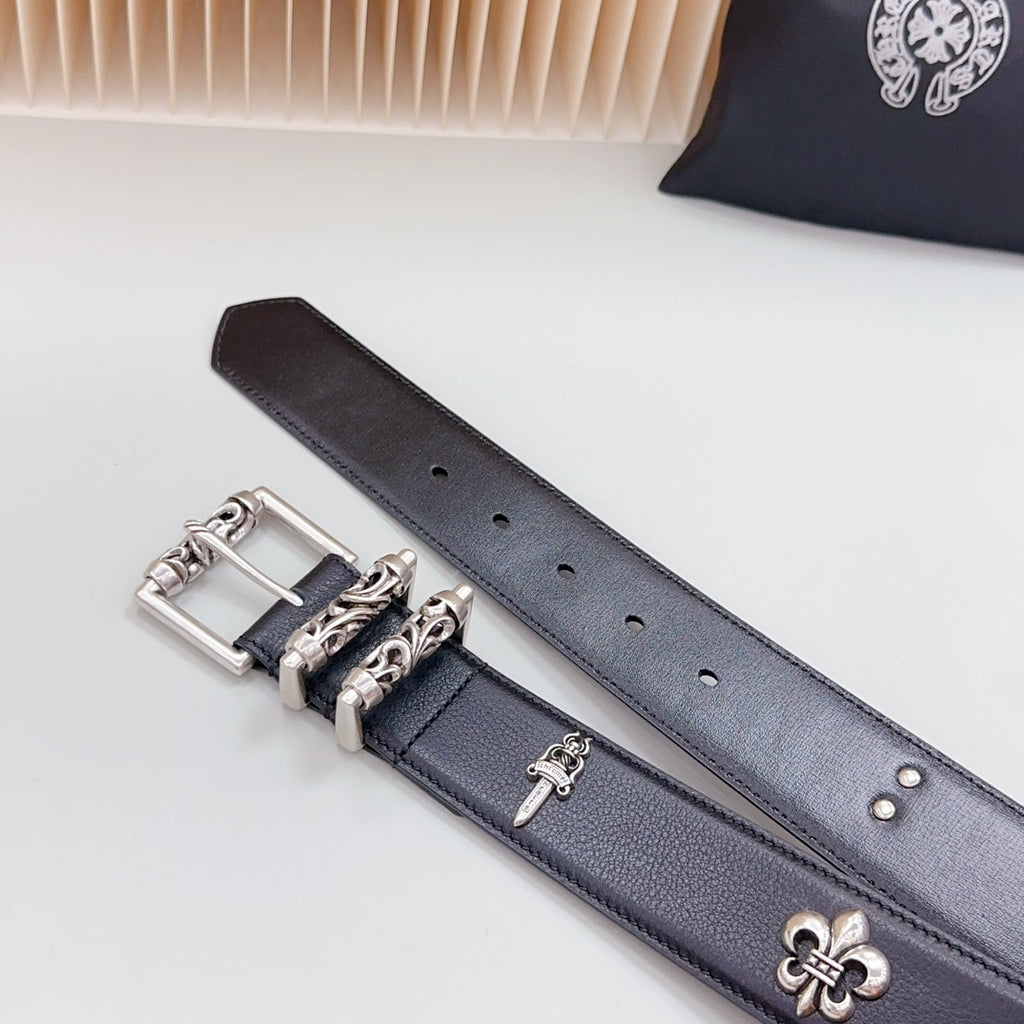 Chrome belt detail of silver buckle and fleur-de-lis emblem on dark leather with studs