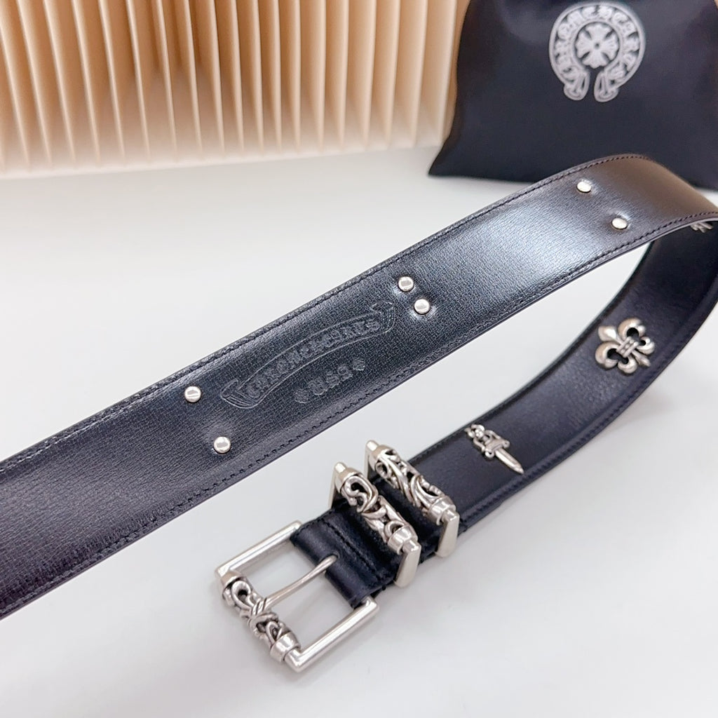 Chrome belt close-up with engraved strap, silver buckle, and fleur-de-lis charm hardware