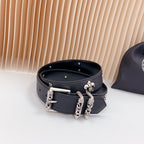 Chrome belt rolled view with silver buckles and chain-like charm accents on dark leather