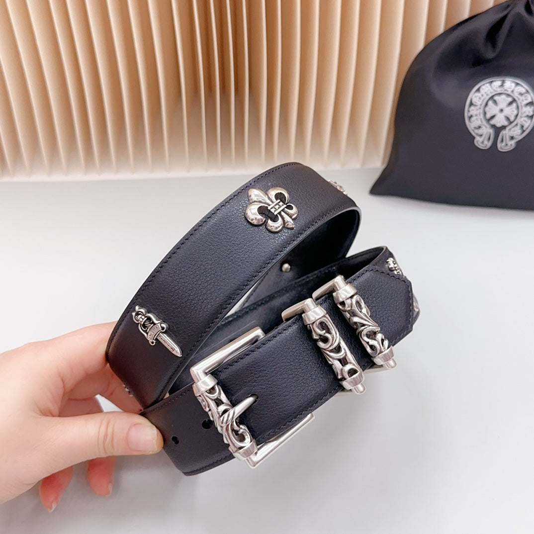 Chrome belt close-up held in hand, dark leather with fleur-de-lis and silver hardware