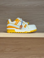 White and yellow low-top trainer sneakers with side emblem and rubber tread sole
