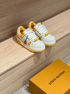Pair of white and yellow low-top trainer sneakers with lace-up closure and chunky sole