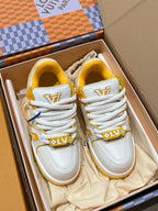 White low-top trainer sneakers in box with white laces, LV-style side logos, yellow trims