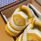 White and yellow low-top trainer sneakers close-up showing side logo on yellow panels