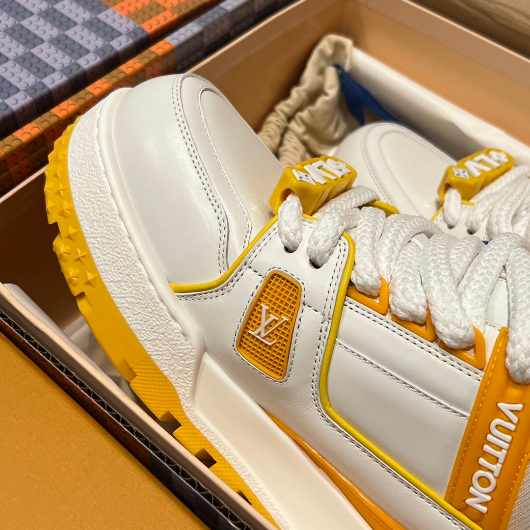 White low-top trainer sneaker detail with white laces, yellow side patch and textured sole