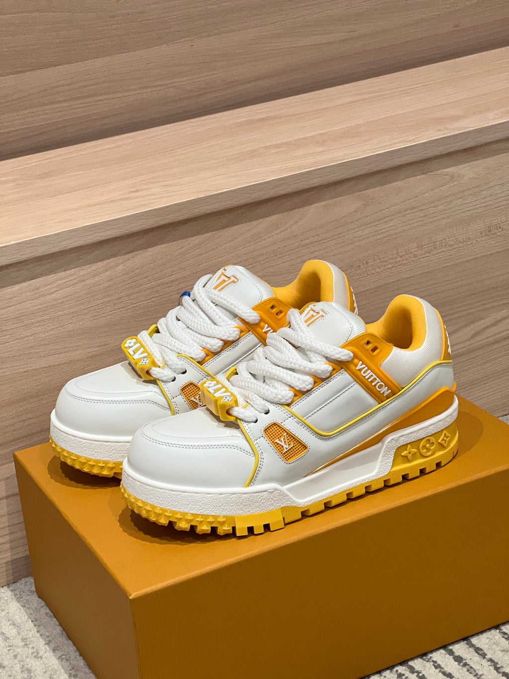 White and yellow low-top trainer sneakers on a yellow shoebox with lace-up design