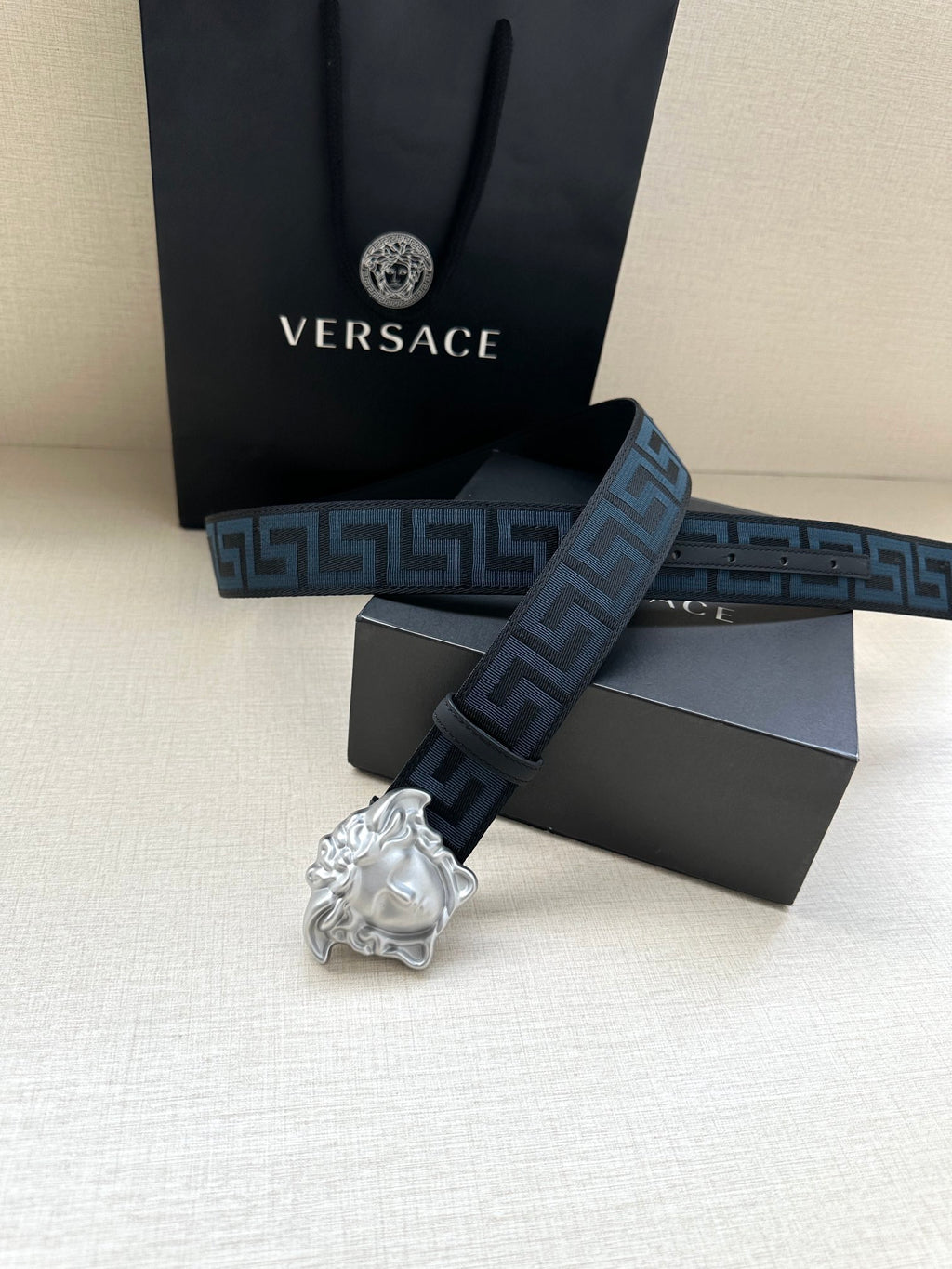 Versace belt showing silver buckle and long dark blue Greek key strap.