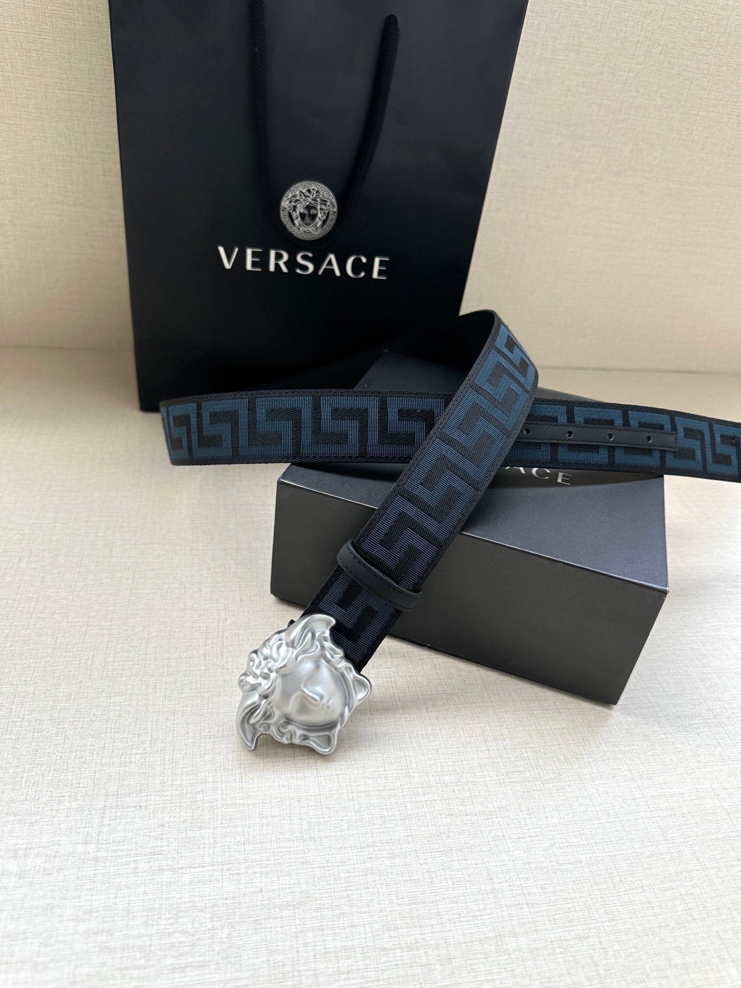 Versace belt showing silver buckle and long dark blue Greek key strap.