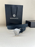 Versace belt with dark blue Greek key strap and prominent silver Medusa buckle.