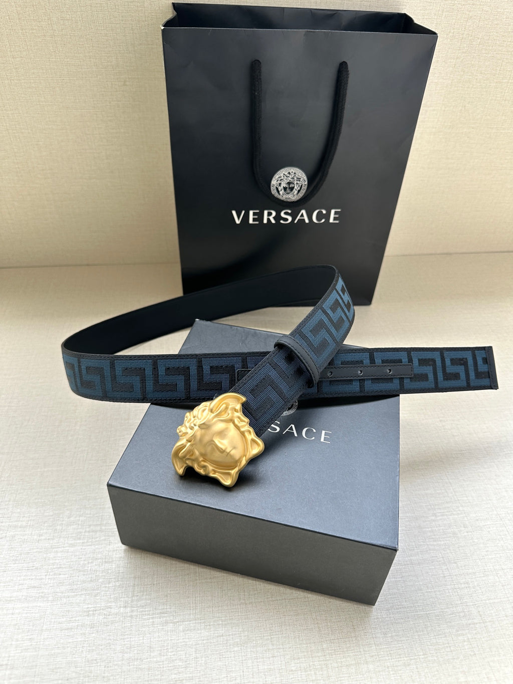 Versace belt with blue Greca strap and gold Medusa buckle on display