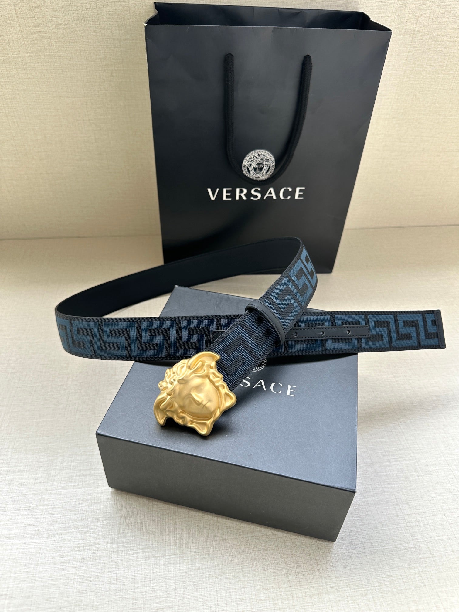 Versace belt with blue Greca strap and gold Medusa buckle on display