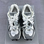 Athletic sneaker pair with white uppers, grey panels, and white laces on a box