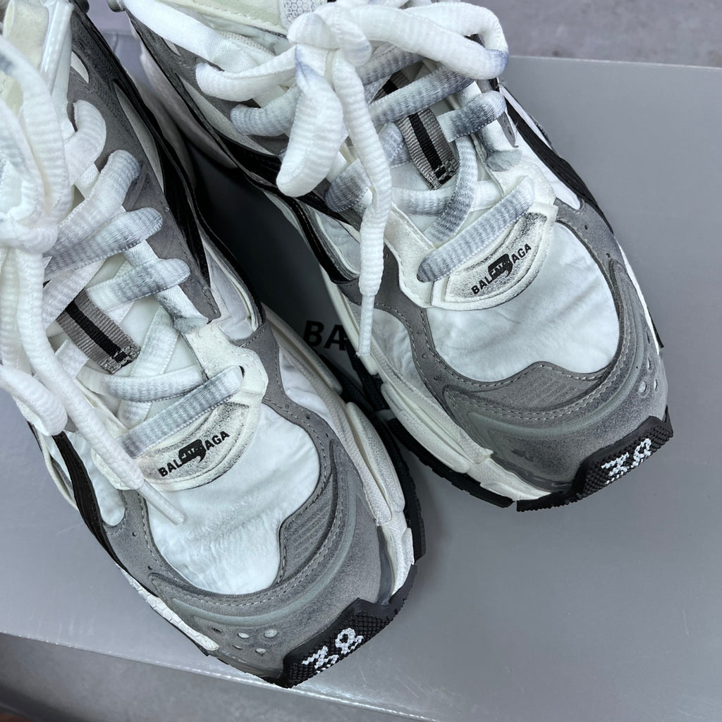 Pair of athletic sneakers showing grey uppers, black overlays, and white lace details