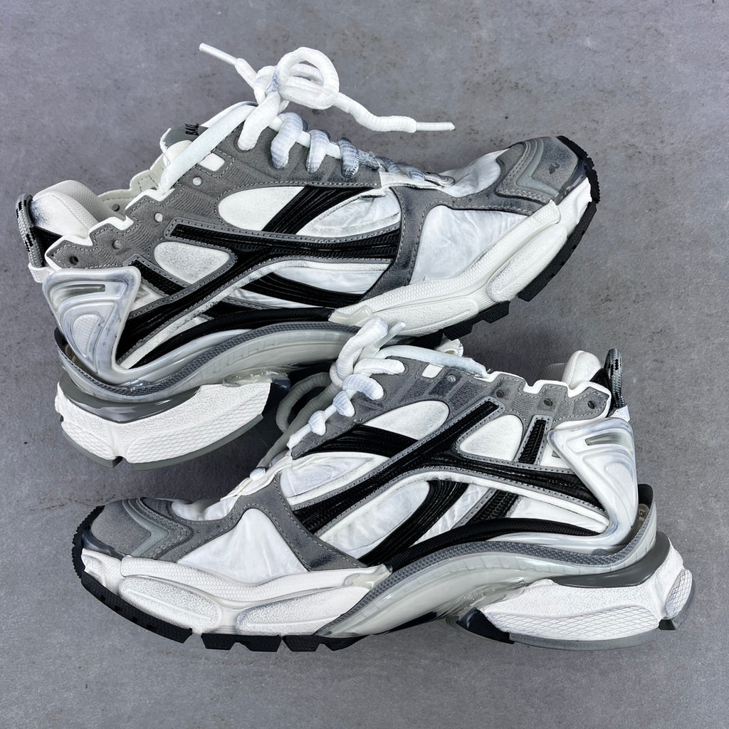 Athletic sneaker pair in grey, white, and black with white laces and sculpted sole