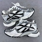 Athletic sneaker pair in grey, white, and black with white laces and sculpted sole