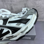 Athletic sneaker side view with grey suede, white panels, black stripe, and laces