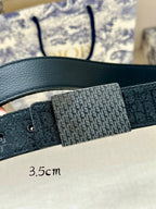 Dior belt close-up: dark leather strap with Dior monogram buckle panel.