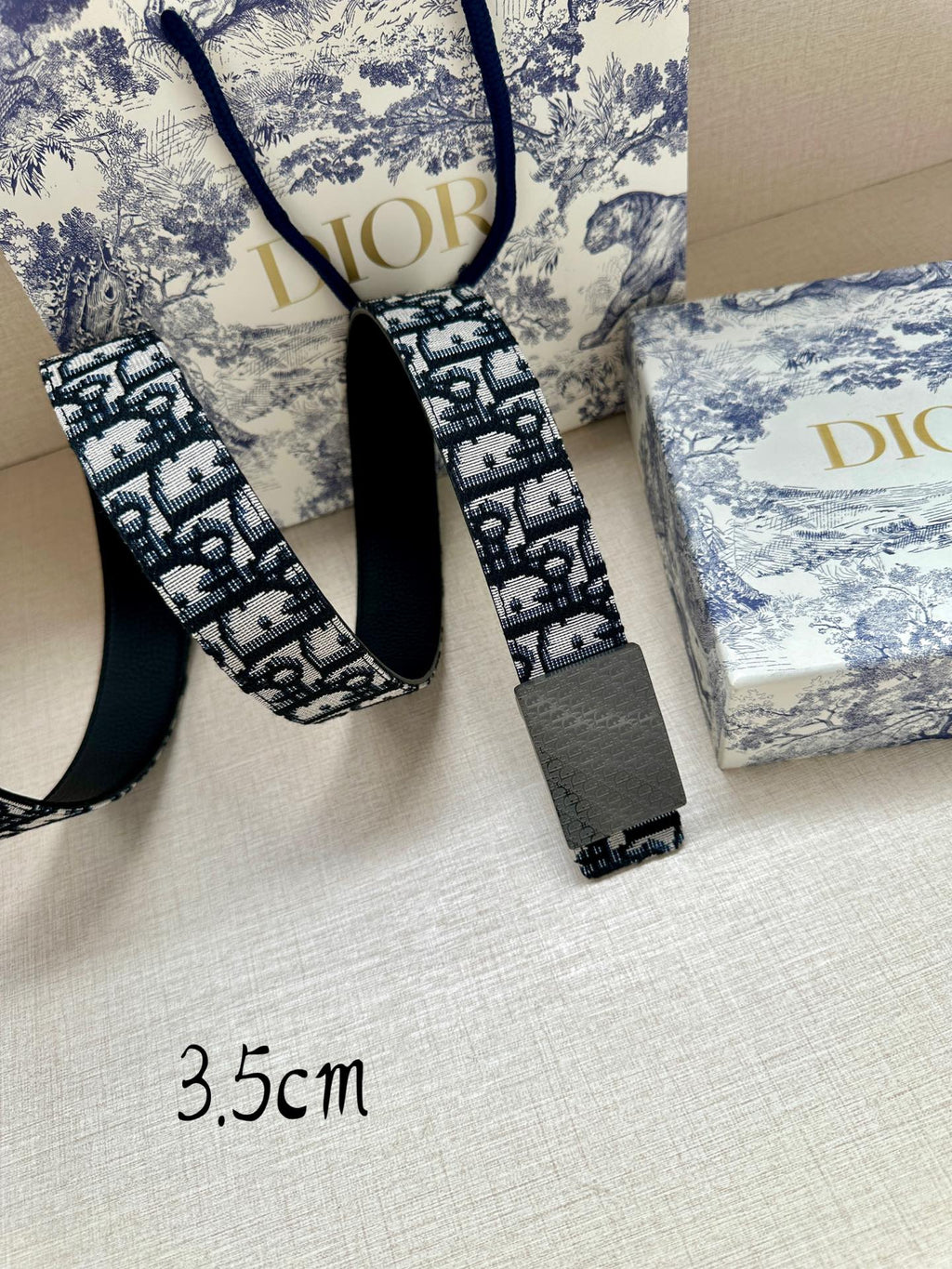 Dior belt with blue logo jacquard and gray buckle, strap ends visible, 3.5cm